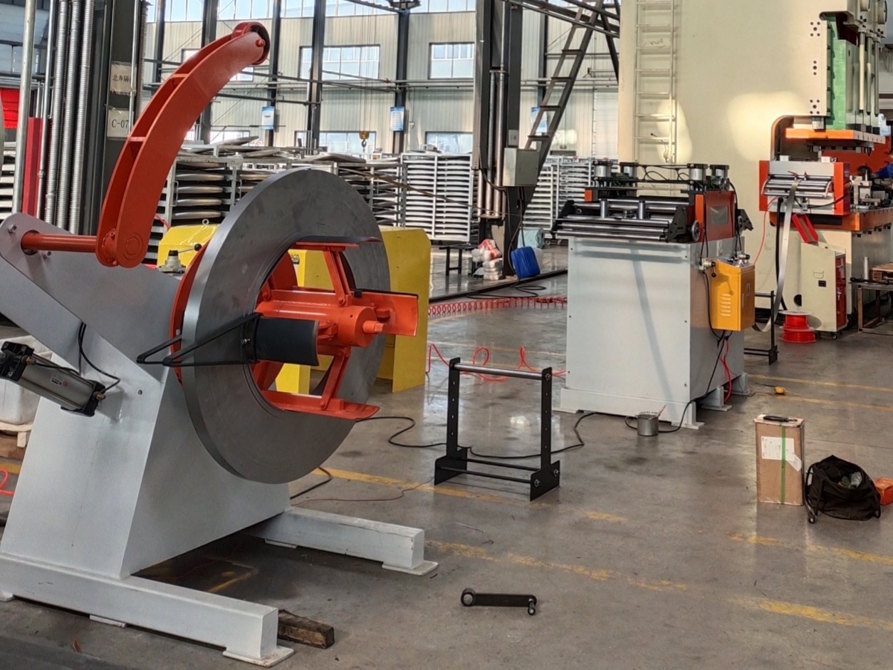 Línea modular HENLI con desbobinador, enderezadora y alimentador instalados frente a una prensa