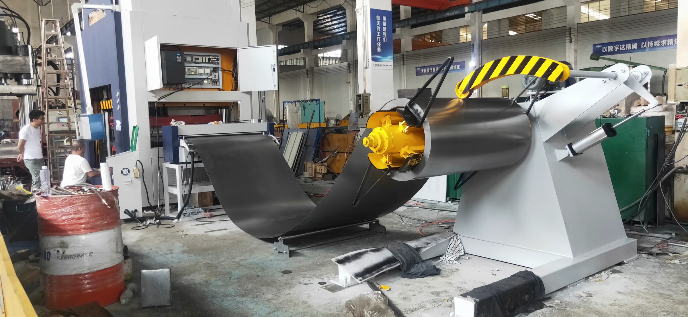 Desbobinador hidráulico HENLI con bobina de acero y brazo presor en una línea industrial