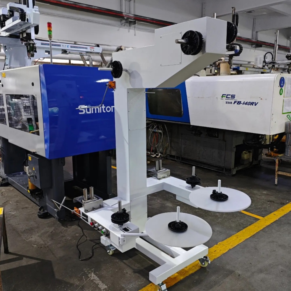 Unidad de recogida intermitente instalada junto a una máquina de moldeo por inyección