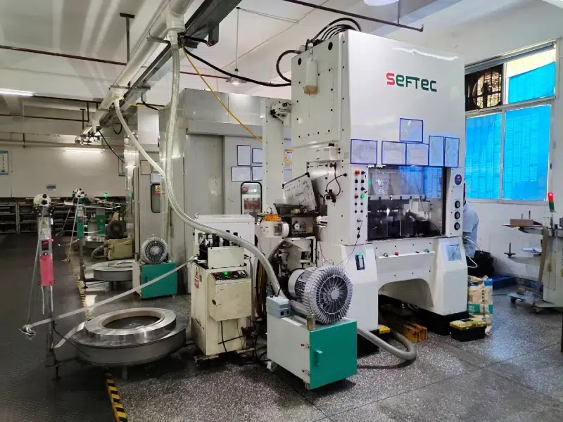 Prensa SEFTEC con unidad XF en primer plano y manguera dirigida al troquel